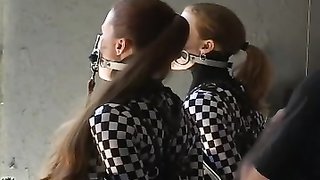 Two redheads in chess-patterned body suits being bound